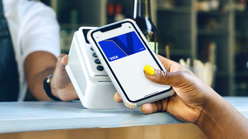 Close up of someone tapping their mobile device to make a payment with their Visa card.