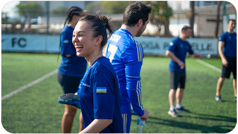 Mulher sorridente jogando futebol com uma camisa azul