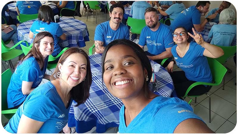 Grupo de pessoas sorridentes em um evento voluntário vestindo camisetas azuis