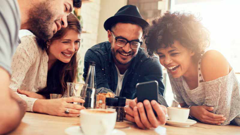 Grupo de amigos sorrindo para a tela de um smartphone