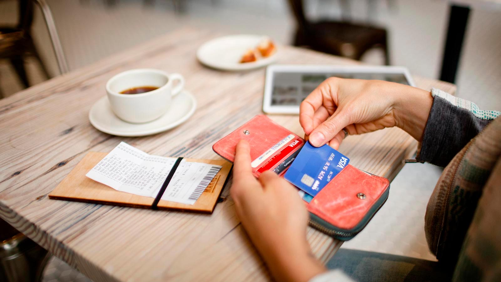 Pessoa retirando cartão da carteira para fazer pagamento num café