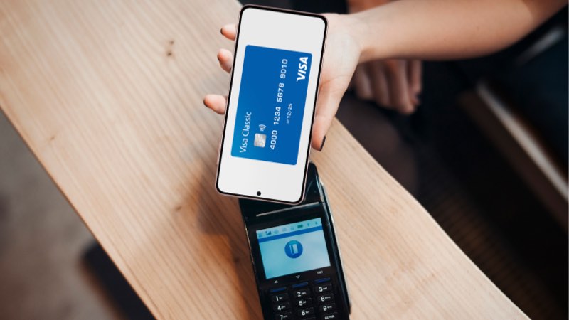 Imagem de uma pessoa com o smartphone na mão pagando por aproximação